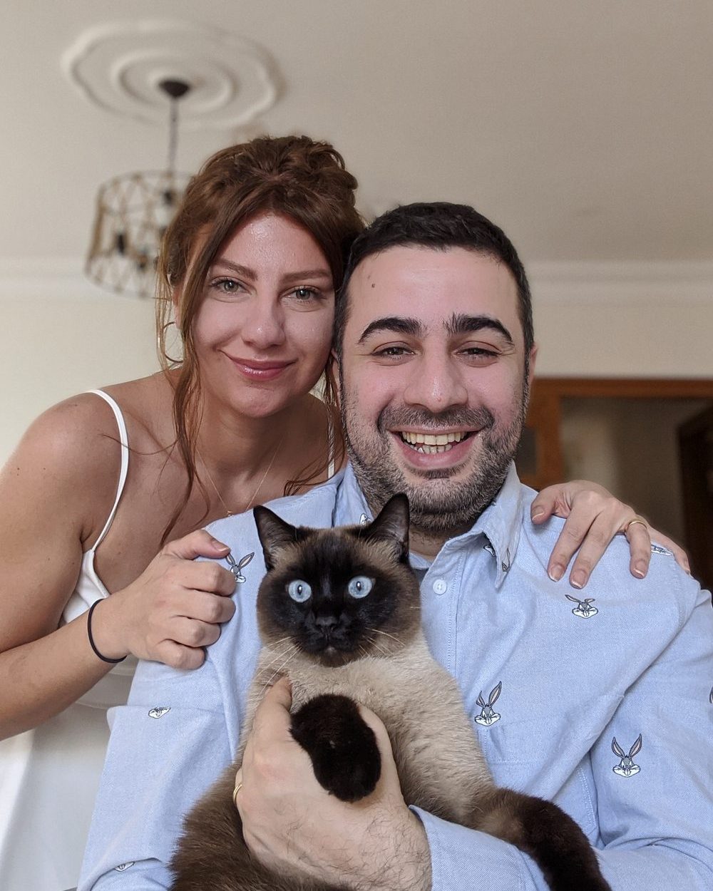 Candas and Ipek smiling with Pipo the Siamese cat